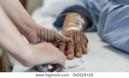 Elderly Senior Aged Patient On Bed With Geriatric Doctor Holding Hands For Trust And Nursing Health 