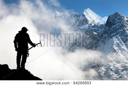 Silhouette Of Man With Ice Axe In Hand And Mountains