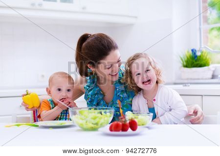 Mother And Children Cooking In A White Kitchen