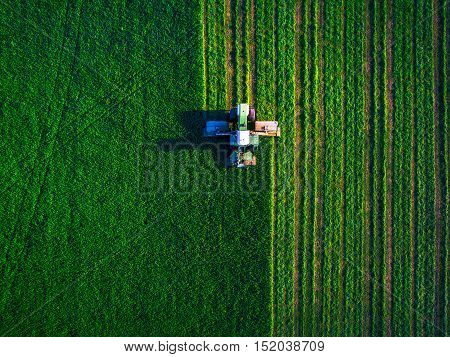 Tractor mowing green field, aerial view, agricultural concept