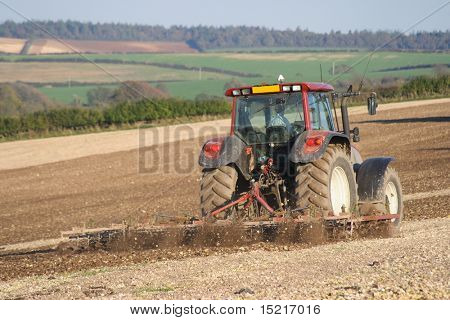 Tractor working on a field preparing the soil for planting.