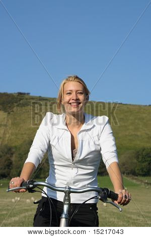 Young woman enjoying a bike ride in the country with rolling hills and blue sky healthy living.