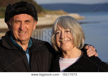 A mature couple enjoy a walk by the seaside in the winter.