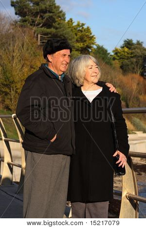 A mature couple enjoy a walk by the seaside in the winter.