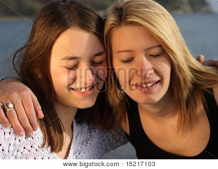 Two sisters make a wish with their eyes shut on holiday by the sea.