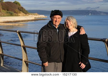 A mature couple enjoy a walk by the seaside in the winter.