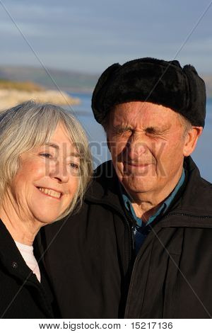 A mature couple enjoy a walk by the seaside in the winter.