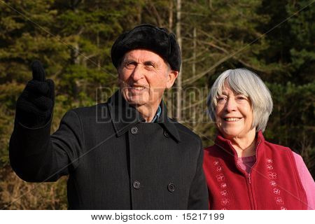 Senior couple enjoy a winter walk through a pine forest.