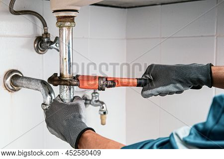 Technician Plumber Using A Wrench To Repair A Water Pipe Under The Sink. Concept Of Maintenance, Fix