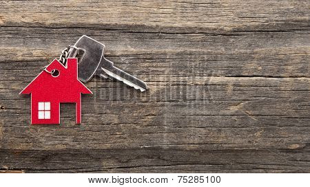 Symbol of the house with silver key on vintage wooden background 