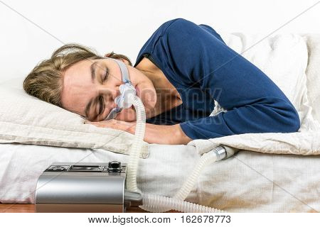 Woman sleeping on her side with CPAP machine in the foreground, sleep apnea treatment.