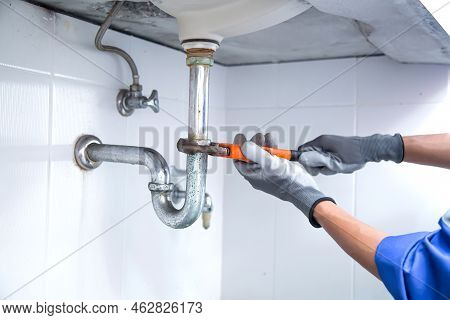 Technician Plumber Using A Wrench To Repair A Water Pipe Under The Sink. Concept Of Maintenance, Fix