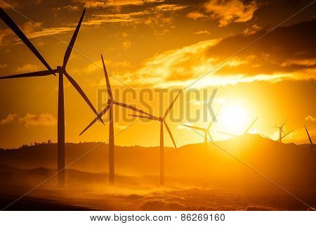 Wind Turbine Power Generators Silhouettes At Ocean Coastline At Sunset. Alternative Renewable Energy