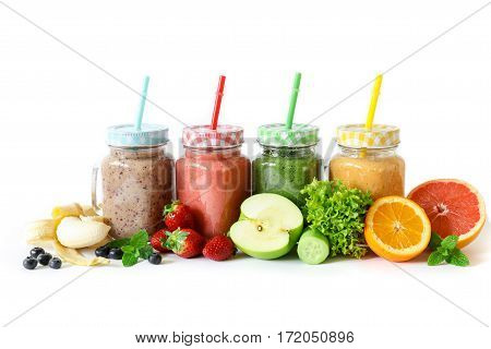 Four different smoothies in a glass jars with vegetables and fruits and ingredients on a white background isolated. Superfood detox and healthy food concept. Horizontal.