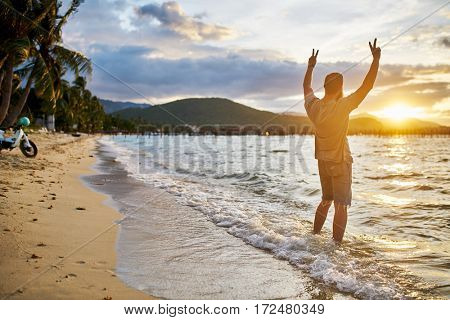 cheering farang man passionately observing sunset by himself in thailand