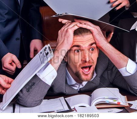 Business people office. Team people are unhappy with their leader. Intern man manager littered with work and does not cope with his duties. Businessman in stress.