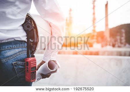 Engineer woman holding white helmet and blueprint with radio for workers security control at power plant energy industry. Engineer Concept