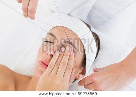 Close up of a hands threading beautiful woman's eyebrow