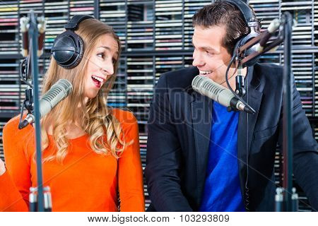 Presenters or moderators - man and woman - in radio station hosting show for radio live in Studio