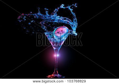 Bright cocktail with lemon in glass and splashing water on dark background