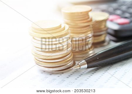 Business, finance, saving money, banking, loan, investment, taxes or accounting concept : Coins stack, calculator, pen and saving account book or financial statement on office desk table