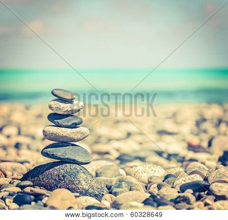 Vintage retro hipster style travel image of Zen meditation background -  balanced stones stack close up on sea beach