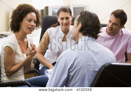 Uomo dà lezione a tre persone In sala Computer