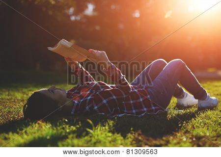 A young woman lying on the grass and reading a book lovely young girl reading a book outdoors