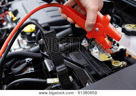 Close-up Of Mechanic Attaching Jumper Cables To Car Battery