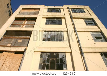 Derelict Building With Broken And Boarded Up Windows.