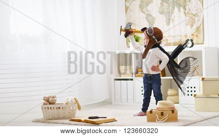 concept of children's dreams and travels. pilot aviator child with a toy airplane plays at home in his room