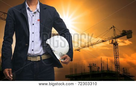 Engineer Man Standing With White Safety Helmet Against Beautiful Dusky Sky With Building Constructio