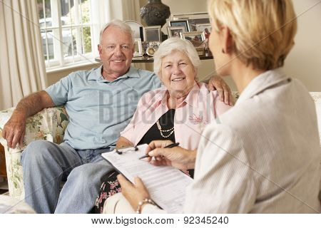 Retired Senior Couple Sitting On Sofa Talking To Financial Advisor