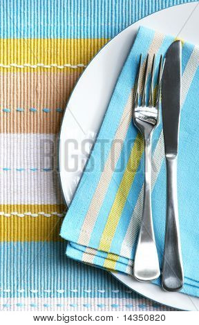 Place cadre avec argent fourchettes et des couteaux sur pastel serviette et set de table correspondante.  Angle vertical.