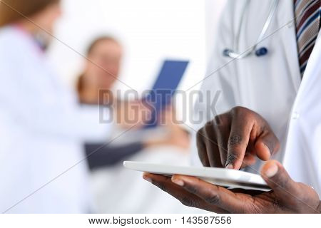 Black male doctor hand point with finger in digital tablet pc touch screen with patient lying in bad in background. Professional equipment therapeutist ward round search opportunities concept