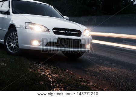 Saratov, Russia - August 28, 2014: Car Subaru Legacy stay on asphalt road near passing cars at dusk