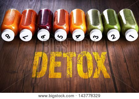 Bottles with delicious detox drinks and text detox on wooden background. Detox diet concept.