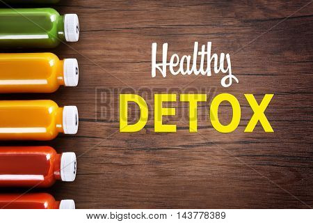 Bottles with delicious detox drinks and text healthy detox on wooden background. Detox diet concept.