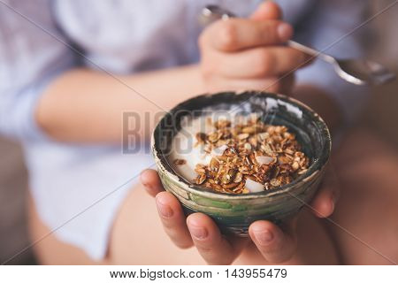 Young woman with muesli bowl. Girl eating breakfast cereals with nuts pumpkin seeds oats and yogurt in bowl. Girl holding homemade granola. Healthy snack or breakfst in the morning.