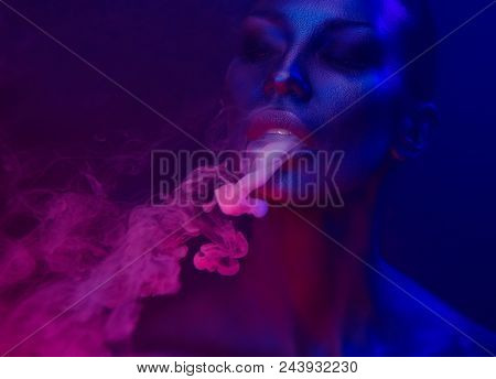 Halloween Vape Party, Nightlife. Beautiful Sexy Young Woman With Glamorous Mystical Makeup Vaping In