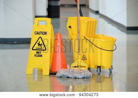 Caution sign with mop and bucket on office floor