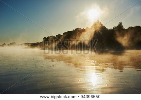 picturesque reflective landscape of foggy misty sunrise over river in summer 