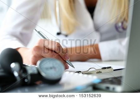 Female medicine doctor hand holding silver pen looking in clipboard pad closeup. Ward round patient visit check 911 medical calculation and statistics concept. Physician ready to examine patient