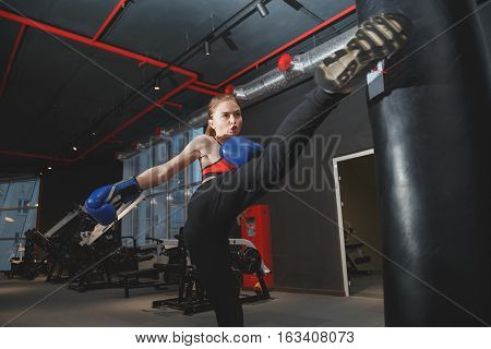 Kickboxing young woman punching kicking the bag