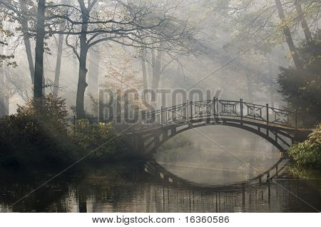 Old bridge in misty autumn park