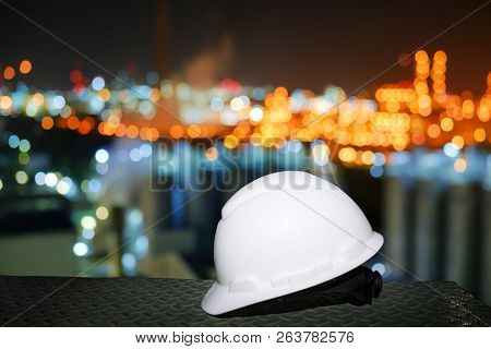 White Safety Helmet On Blurred Lights Industrial Plant Background, Worker At Night Concept In Petroc