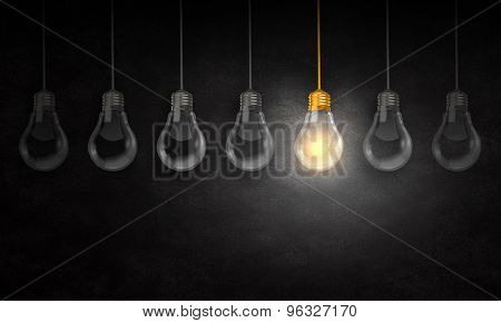 Illuminating hanging light bulb on dark background