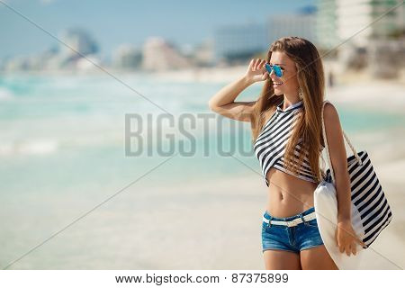 Portrait of happy sexy girls with beach bag posing against the sea.