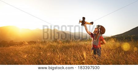 Child pilot aviator with airplane dreams of traveling in summer in nature at sunset