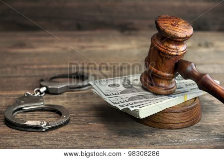 Dollar Banknotes, Handcuffs And Judge Gavel On Wood Table